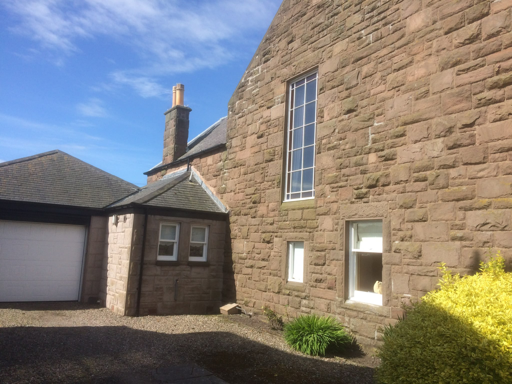 White-painted windows on a sandstone house, including a tall stair window.